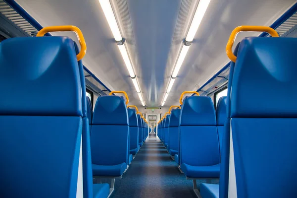 Inside of a train cabin with blue seats and sunlight coming in through the windows
