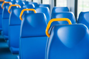 Mavi koltuklu bir tren kulübesinin içinde ve pencereden içeri güneş ışığı giriyor.