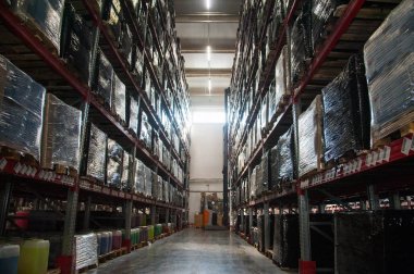 Deponun içinde. Kutularla dolu raflar. Depoda forklift yükleyicisi.