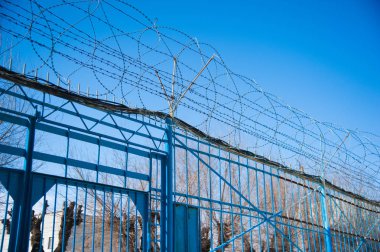 Hapishane duvarlarının etrafına dikenli teller gerilmiş.