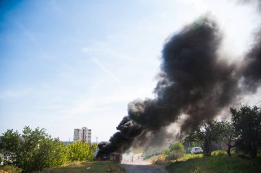 Şehrin yakınındaki alanda ateş. Siyah arka planda şehir ateşten duman