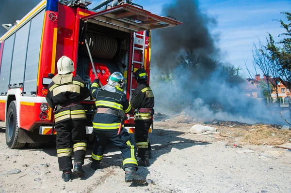 Fire in the field near the city. Firefighter extinguishes a fire