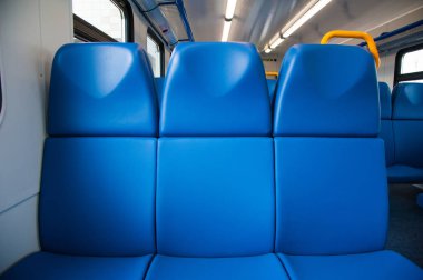 Mavi koltuklu bir tren kulübesinin içinde ve pencereden içeri güneş ışığı giriyor.