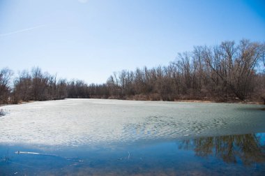 Erken baharda ormandaki nehir sessizce akan akar olduğunda hala buz ve kar. Bahar manzara