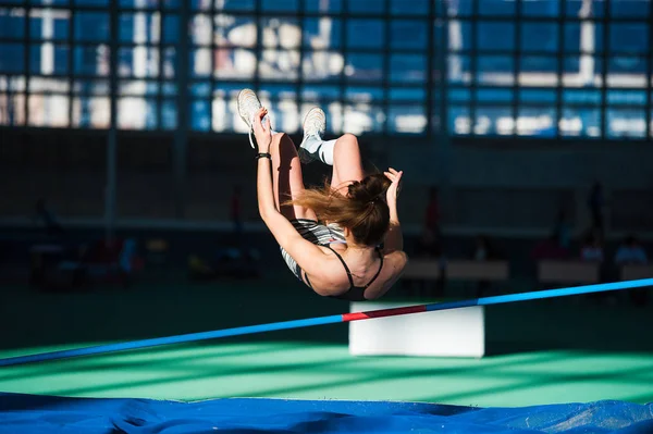 Mulher pulando sobre bar na reunião de atletismo — Fotografia de Stock