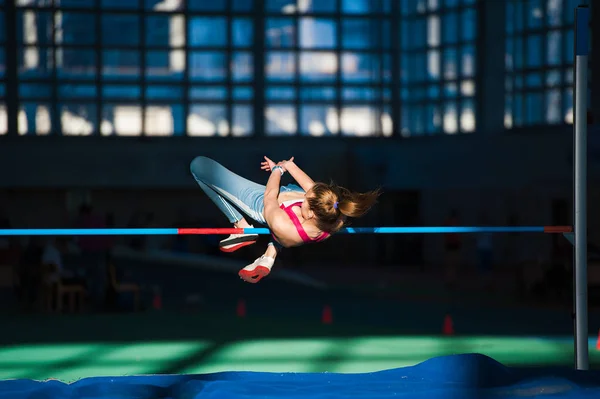 Woman jumping over bar at athletics meeting — Stock Photo, Image