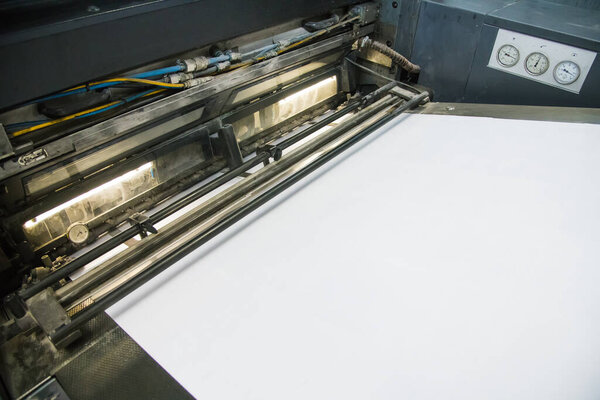 Printing presses at work in the printing. Printed sheets of paper are served in the printing press