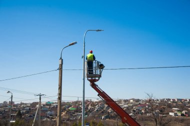 Elektrikçiler elektrik direğindeki elektrik hattını tamir ediyorlar.