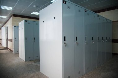 Spor kulübünde, okulda, bölümde boş bir soyunma odası. Sıralı dolaplar, numaralar, kilitler ve duş..