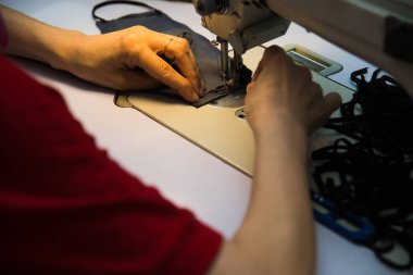 Dikiş makinesinde kadın eli. Ekipmanlarının arkasında çalışan bir terzi. Terzilik süreci, tasarım atölyesi, giyim endüstrisi konsepti