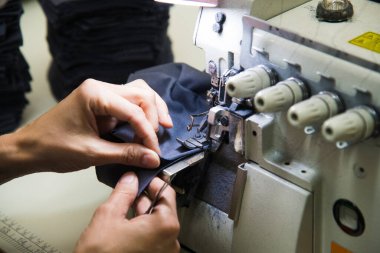 Dikiş makinesinde kadın eli. Ekipmanlarının arkasında çalışan bir terzi. Terzilik süreci, tasarım atölyesi, giyim endüstrisi konsepti