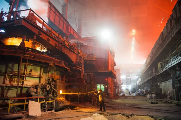 Metal structures and buildings of the old metallurgical plant inside and outside. The process of melting metal. Steelworker at work. Products of the metallurgical enterprise.