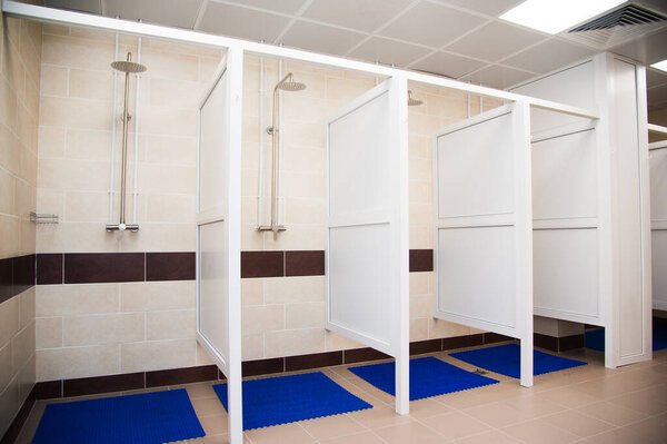 Showers in a public shower with tiles and lighting. Common showers in the fitness room or pool