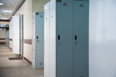 Spor kulübünde, okulda, bölümde boş bir soyunma odası. Sıralı dolaplar, numaralar, kilitler ve duş..