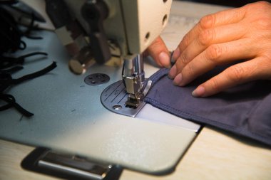 Dikiş makinesinde kadın eli. Ekipmanlarının arkasında çalışan bir terzi. Terzilik süreci, tasarım atölyesi, giyim endüstrisi konsepti