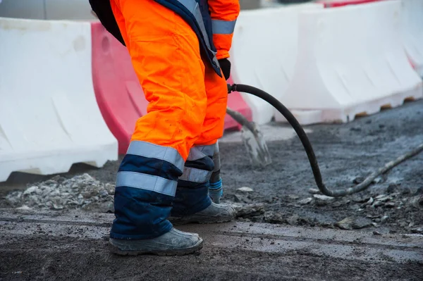 Yol işçisi yol yapımı sırasında eski asfaltı kaya matkabıyla temizliyor.