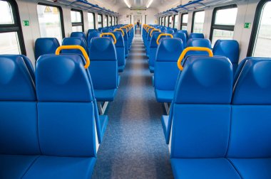 Mavi koltuklu bir tren kulübesinin içinde ve pencereden içeri güneş ışığı giriyor.