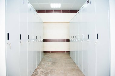 Spor kulübünde, okulda, bölümde boş bir soyunma odası. Sıralı dolaplar, numaralar, kilitler ve duş..