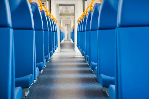 Inside of a train cabin with blue seats and sunlight coming in through the windows