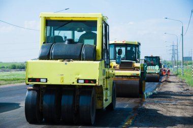 Eskisinin tamiri ve yeni bir asfalt yol inşaatı. Yeni yol inşaatında kazıcılar, grevciler ve yol silindirleri çalışıyor.