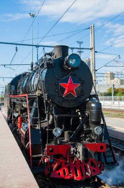 Klasik siyah buhar lokomotifi. Tren istasyona vardı. Sürücü platformda