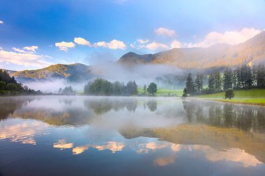 foggy morning landscape in Alps mountain and lake with reflectio clipart