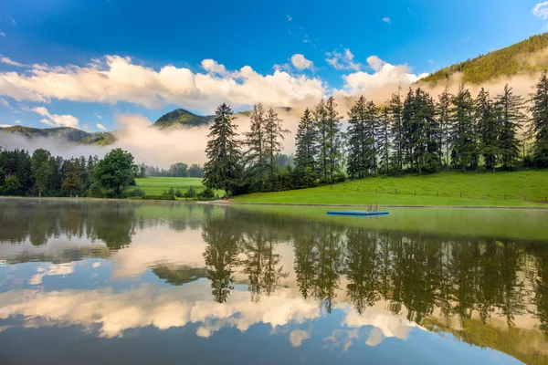 Віддзеркалення неба та дерев у спокійному озері в горах — стокове фото