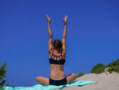 Siyah bikini yoga poz yapıyor ince ve atletik kız, calisthenics, fitness eğitimi, mavi gökyüzü ile bir plajda egzersiz, fitness-wellness