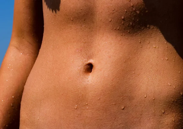 Beautiful athletic tanned belly with cute navel. A flat, slim, muscular and firm belly with a flawless bellybutton.