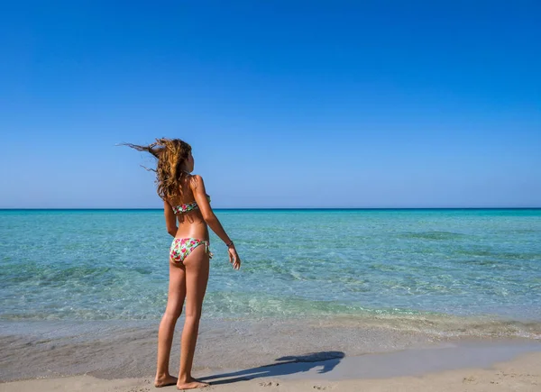 Turkuaz su ile harika bir plajda renkli bir bikini sportif tabaklanmış kız