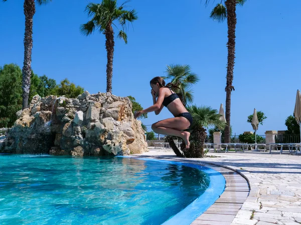 Güzel atletik güneş tabaklanmış kız tatilde bir yüzme havuzunda ferahlatıcı bir dalış alarak