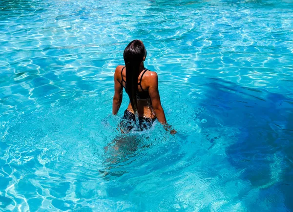 Tatilde bir yüzme havuzunda sıçrayan Pretty atletik güneş tabaklanmış kız tabaklanmış