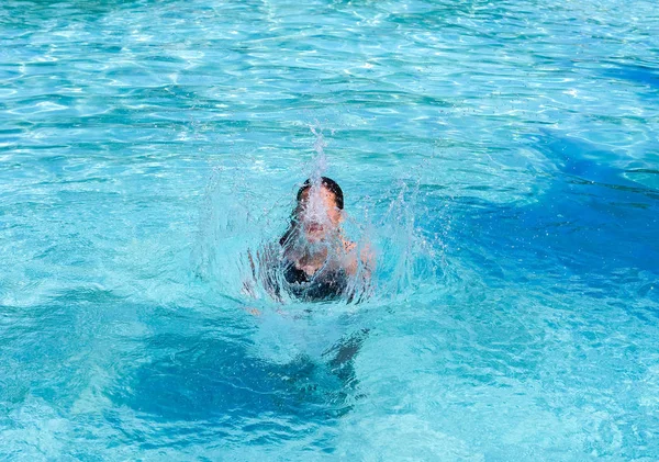 Довольно спортивная загорелая девушка, плескающаяся в бассейне в отпуске — стоковое фото