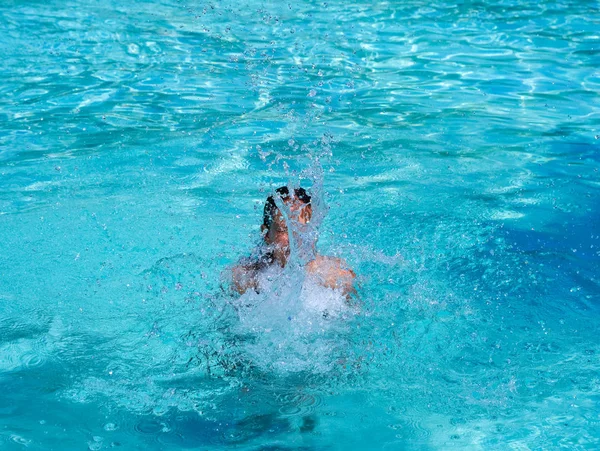 Pretty athletic sun tanned girl splashing in a swimming pool on vacation — Stock Photo, Image