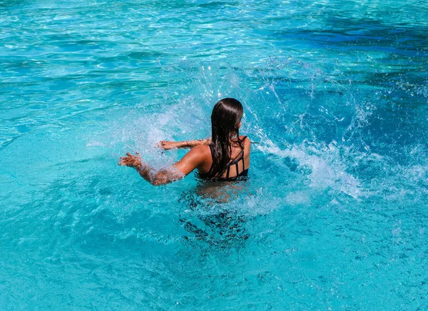 Tatilde bir yüzme havuzunda sıçrayan Pretty atletik güneş tabaklanmış kız tabaklanmış