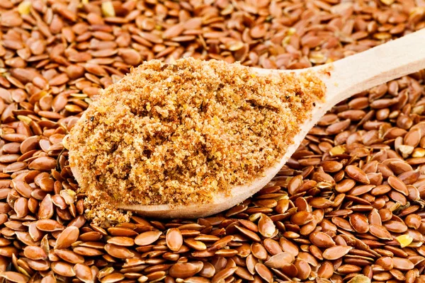pile of flax seeds with crushed seeds in wooden spoon