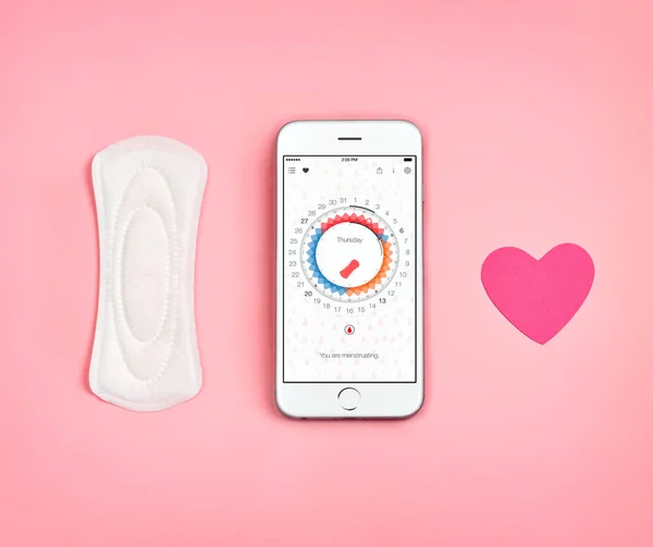 Phone with menstrual calendar. Sanitary napkin and heart symbol on pink background. Concept of critical days, menstruation