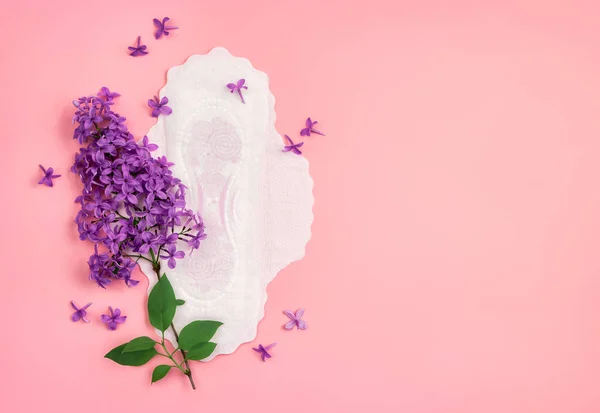 Sanitary napkin with lilac flower on pink background. Concept of critical days, menstruation