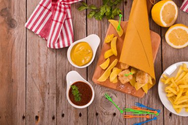 Balık ve cips kesme tahtası üzerinde hardallı.