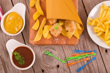 Balık ve cips kesme tahtası üzerinde hardallı.