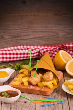 Balık ve cips kesme tahtası üzerinde hardallı.