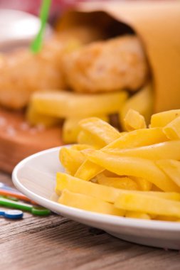 Balık ve cips kesme tahtası üzerinde hardallı.