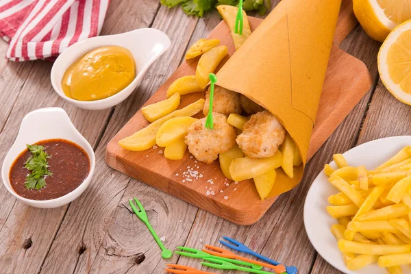 Balık ve cips kesme tahtası üzerinde hardallı.