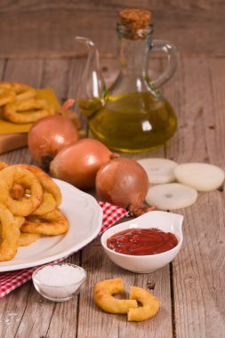 Soğan halkaları ketçap ve hardal beyaz çanak üzerinde.