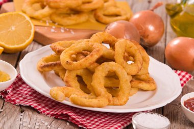 Soğan halkaları ketçap ve hardal beyaz çanak üzerinde.