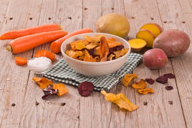 Ahşap masa üzerinde karışık sebze cips.