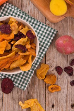 Ahşap masa üzerinde karışık sebze cips.