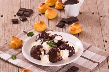 Beyaz çanak üzerinde çikolatalı profiterol.