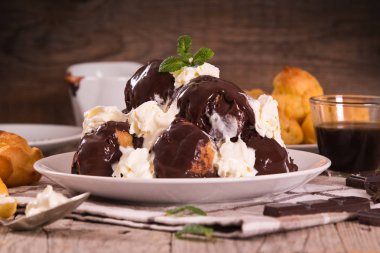 Beyaz çanak üzerinde çikolatalı profiterol.