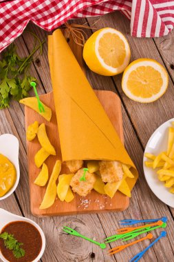 Balık ve cips cuttingboard üzerinde.